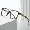 Black rectangular eyeglasses with a tortoiseshell accent on the temple, resting on a white surface.