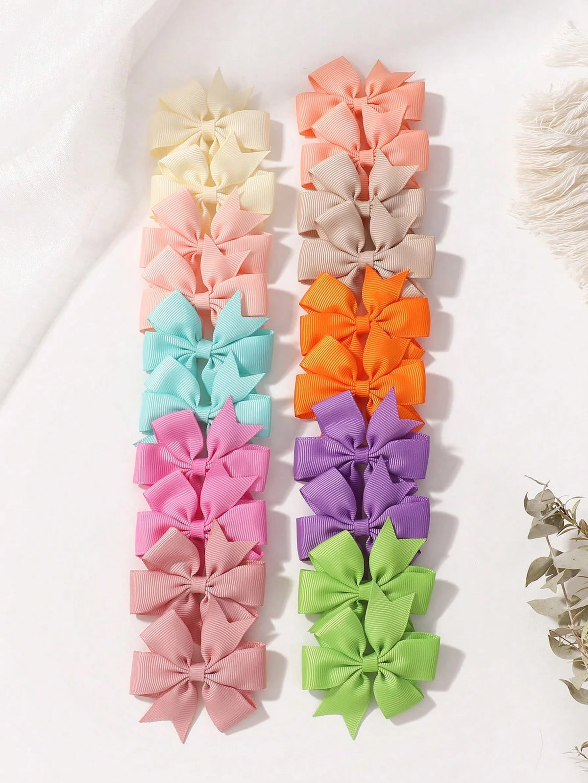 Assorted grosgrain ribbon hair bow clips in pastel shades of pink, peach, yellow, and green.