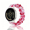 Une montre avec un bracelet en résine élastique marbré rose et blanc, présentée sur une surface réfléchissante.