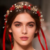A close-up of a model wearing a red rose pearl crystal headband with red ribbons.