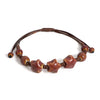 A handmade glazed ceramic star bracelet with dark brown beads and a leather cord.
