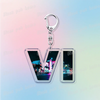 Silver keychain featuring a stylized V logo with neon city lights in the background