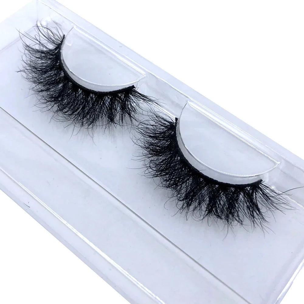 A pair of natural mink false eyelashes displayed in a clear plastic container.