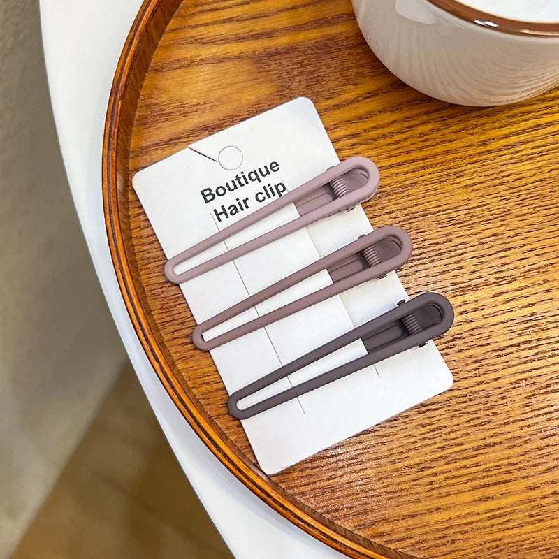 A set of vintage frosted geometry hair clips displayed on a white card on a wooden surface.