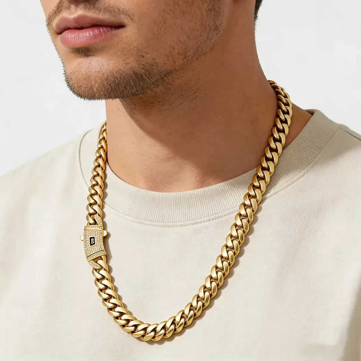 A close-up of a male wearing a gold-plated Miami Cuban chain necklace against a light-colored shirt.