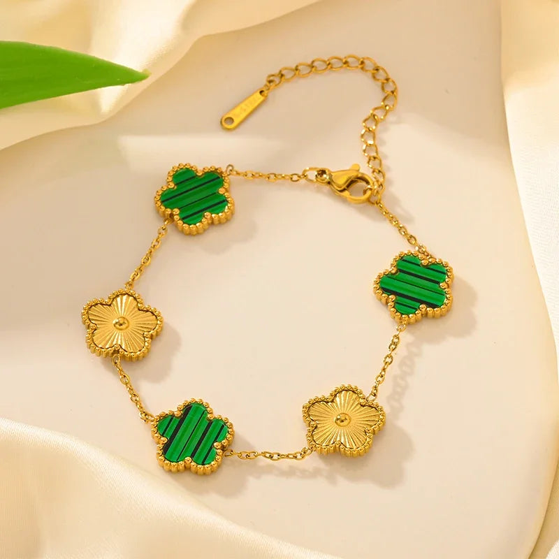Gold plated stainless steel double-sided petal bracelet with green enamel accents on a cream background