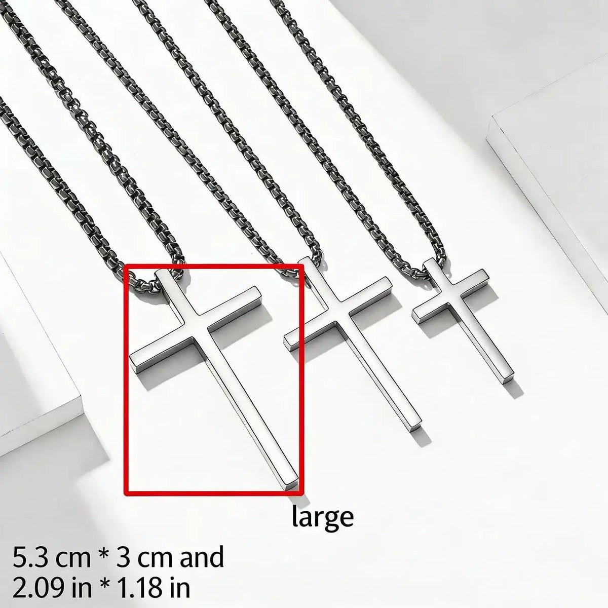 Three stainless steel cross pendant necklaces of different sizes displayed on a white background