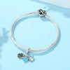A silver bracelet featuring a family tree charm and a heart pendant on a light blue background.