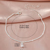 A delicate sparkling zircon heart cross anklet displayed on a pink fabric background.