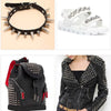 A black leather handbag decorated with silver bullet rivets and studs, shown next to a studded black leather jacket.