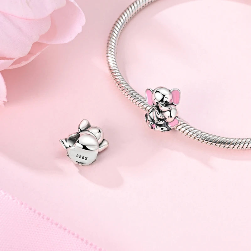 A sterling silver devil's eye charm bracelet with a small elephant charm displayed on a pink background.