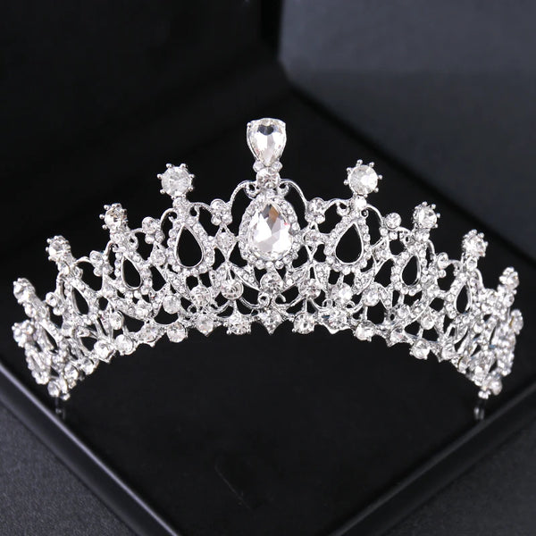 Tiara y corona de adorno de cabello con incrustaciones de cristal brillante, exhibida sobre una superficie de terciopelo negr