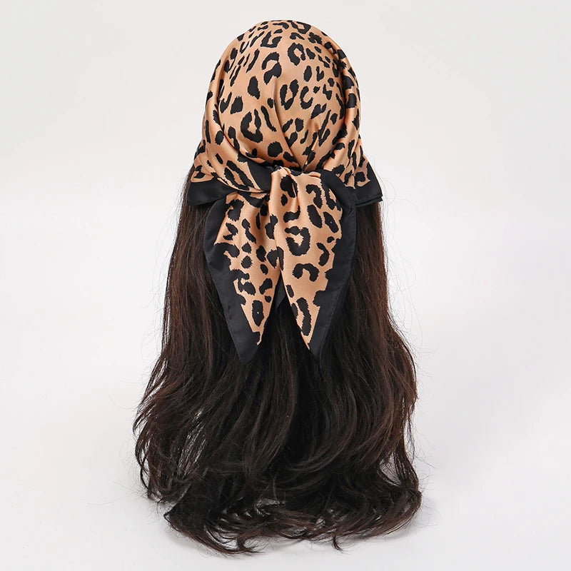 Schwarzer Satin-Schal mit Leopardenmuster, gebunden um einen dunkelbraunen Pferdeschwanz.