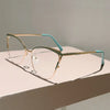 Un par de gafas de computadora con montura metálica dorada y detalles azul claro, sobre una superficie blanca.
