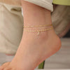 Pulsera de oro con dije de la letra A, usada en el tobillo.