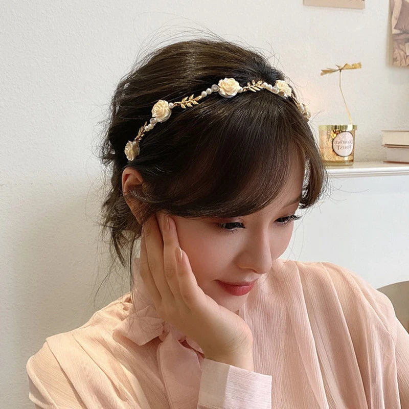 A close-up of a woman wearing an elegant rose vine headband hair accessory.