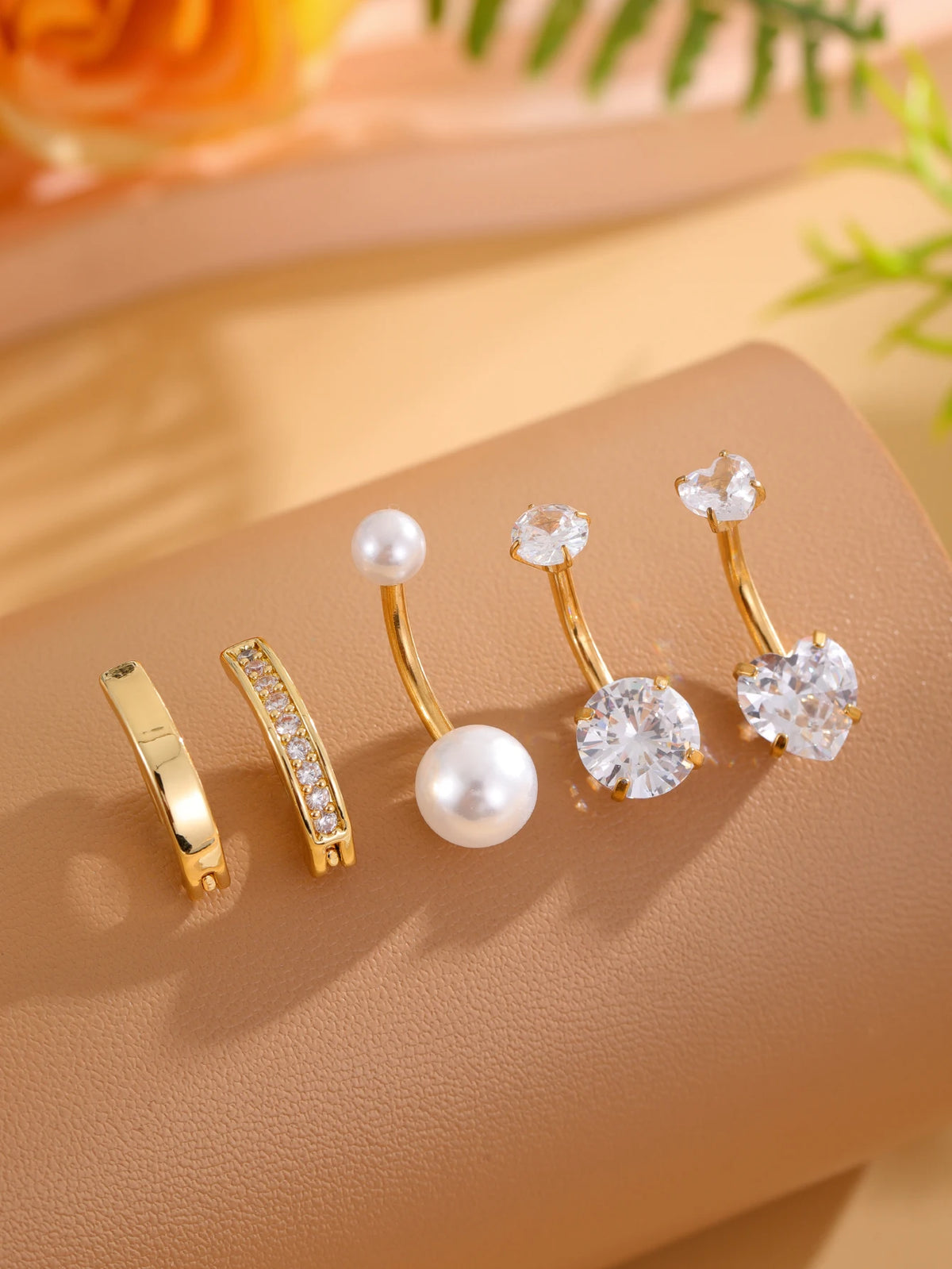A set of five gold stainless steel dangled belly button rings featuring pearl and diamond accents.