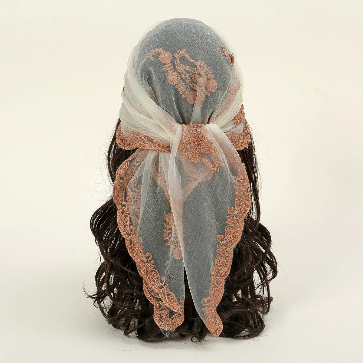 A floral embroidered lace bandana headscarf tied around dark, curly hair.