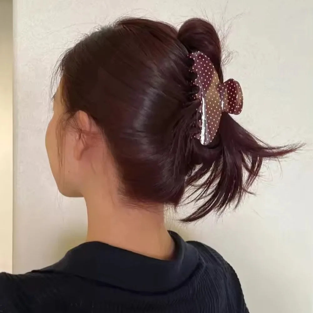 Primer plano del cabello castaño oscuro de una mujer peinado en coleta alta con horquillas decorativas.