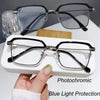 A pair of black photochromic reading glasses with silver frames resting on a white surface.