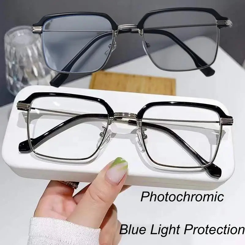 A pair of black photochromic reading glasses with silver frames resting on a white surface.