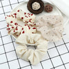 A set of three knitted hair scrunchie headbands in cream and beige colors with various patterns displayed on a white plate.