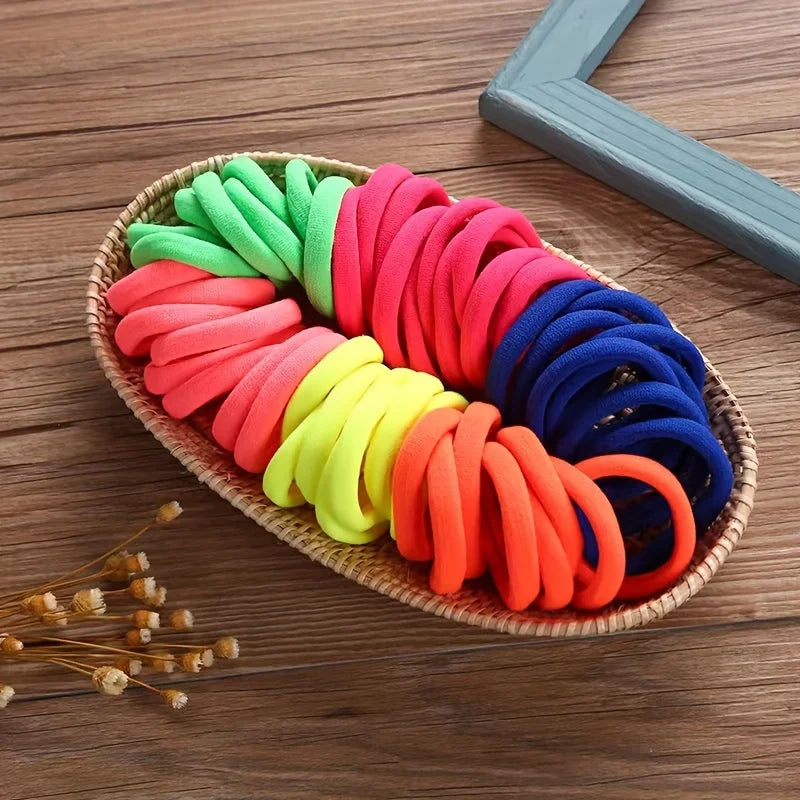 A colorful arrangement of boho seamless elastic hair ties in shades of green, pink, yellow, and blue on a wooden surface.