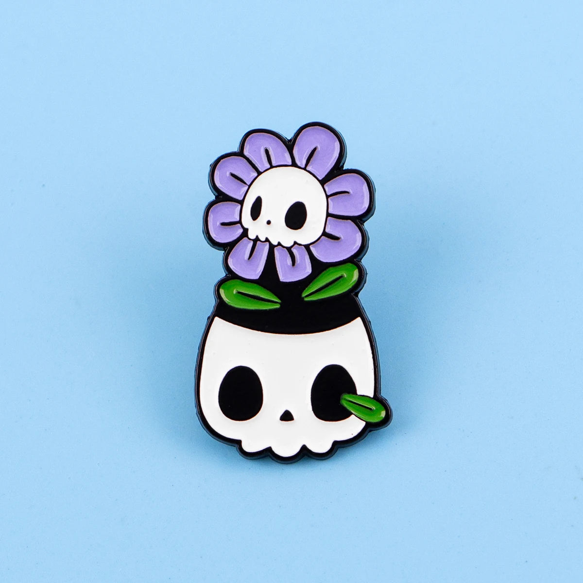 An enamel pin featuring a purple flower skull design with green leaves.