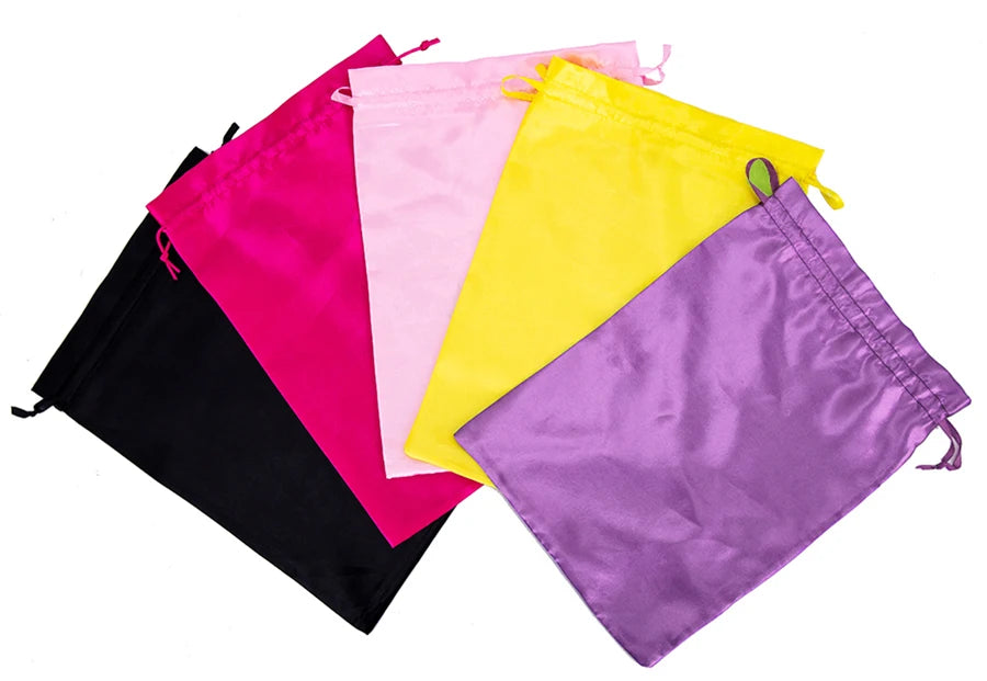 A collection of satin wig storage bags in pink, yellow, purple, and black with drawstrings.