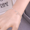 A close-up of a sterling silver double heart charm bracelet worn on a wrist.