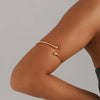 A close-up of a woman's arm showing gold droplet arm bangles on the wrist.