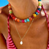 A close-up of a colorful resin beaded statement choker necklace worn around the neck.