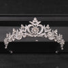 A silver crystal rhinestone bridal tiara headpiece with intricate floral and heart designs.