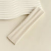 A beige fabric headband is shown next to a wavy white background.