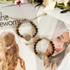 A set of gold-toned medal charm bracelets with dark olive beads displayed next to a woman's portrait.