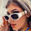 Eine Frau trägt weiße Vintage-Luxus-Square-Sonnenbrille mit goldenen Akzenten.