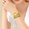 A close-up of a woman wearing a gold-toned quartz snake design watch on her wrist.