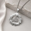 Silver pendant necklace featuring the Arabic calligraphy of Ayatul Kursi on a smooth, light-colored stone background.