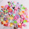 A colorful set of 10 resin nail art charms featuring various shapes and glitter in pink, purple, green, and yellow.