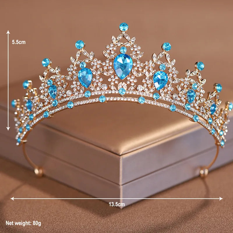 A sparkling crystal baroque bridal tiara headpiece featuring blue gemstones displayed on a box.