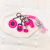 A pink fitness keychain set featuring a fitness disc, a weight, and a pink cord.