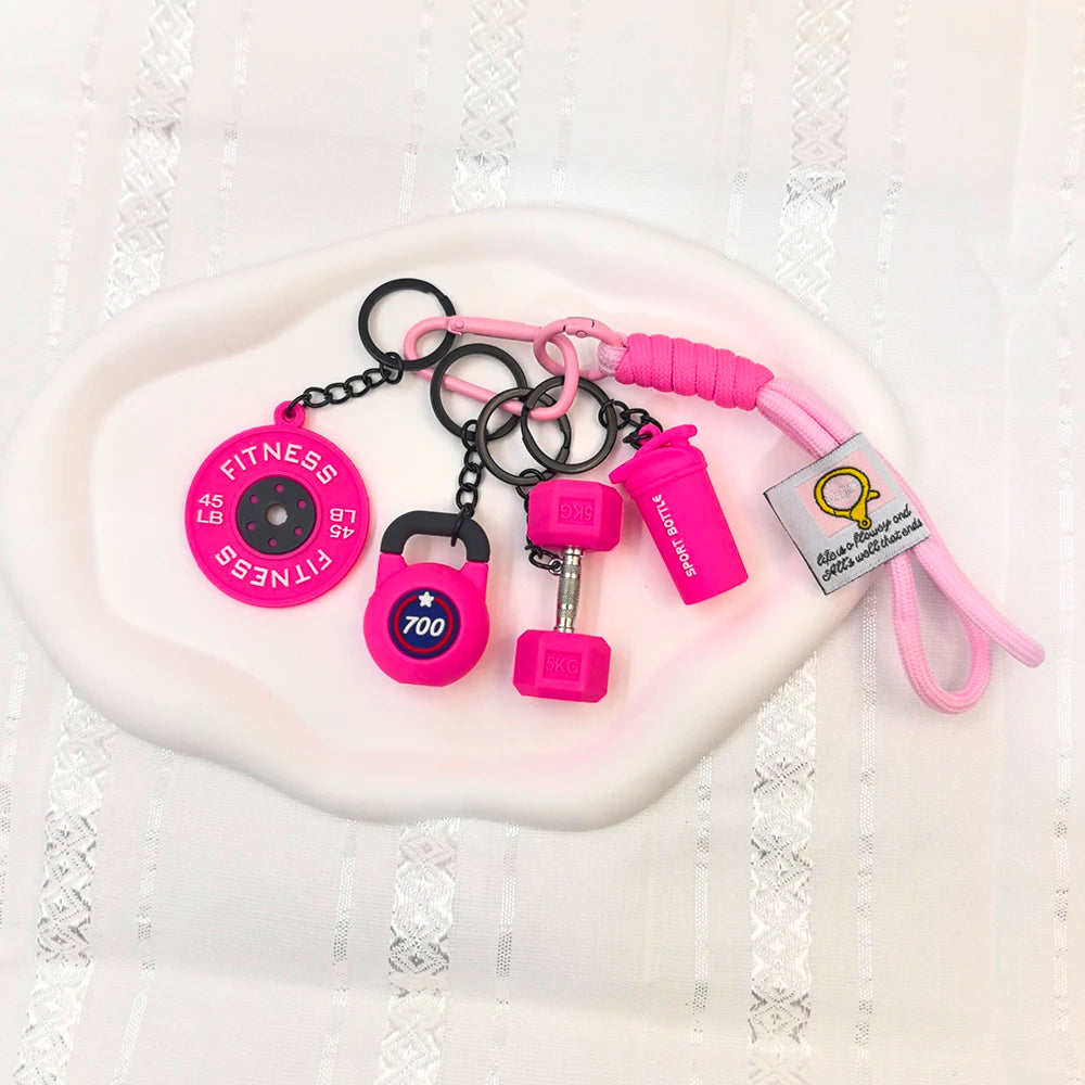 A pink fitness keychain set featuring a fitness disc, a weight, and a pink cord.