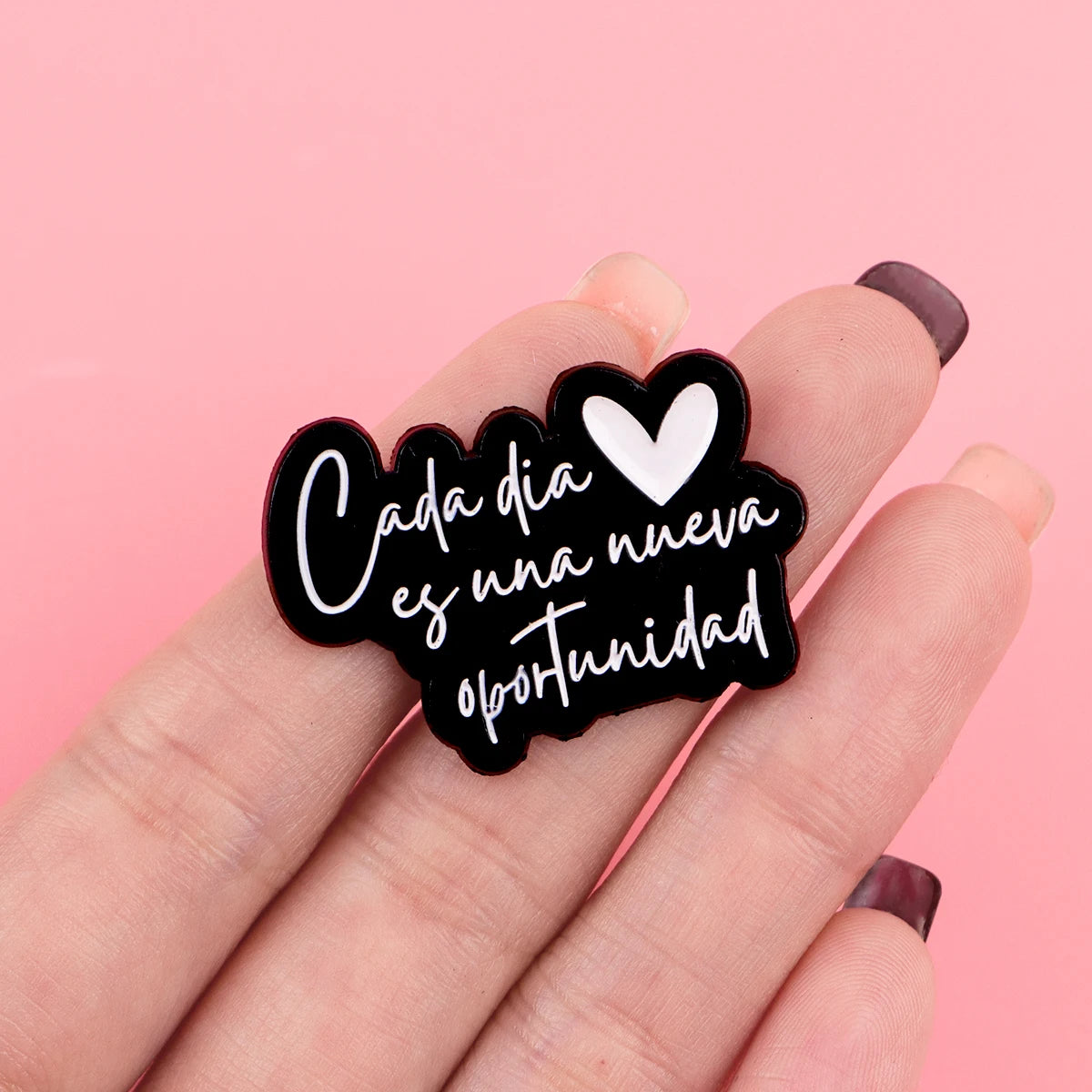 Pin de solapa de esmalte negro con corazón blanco y texto que dice Cada día es una nueva oportunidad