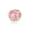 Una cuenta redonda con tonos rosa y oro rosa y intrincados patrones florales.