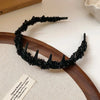 Black resin wave toothed headband displayed on a wooden platter.