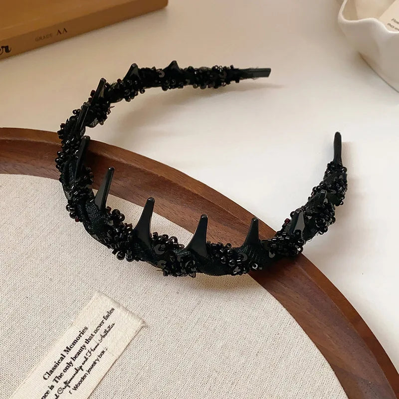 Black resin wave toothed headband displayed on a wooden platter.