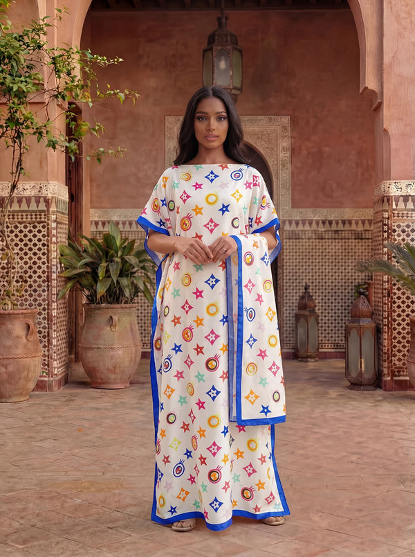 A woman wearing a floral print satin maxi shawl in white and blue tones stands in an arched outdoor setting.