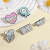 A collection of enamel pins featuring funny work quotes and a skull design on a light yellow background.