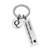 Silver keychain with a circular charm featuring a stylized 'Q' and a tag that reads I need you here with me