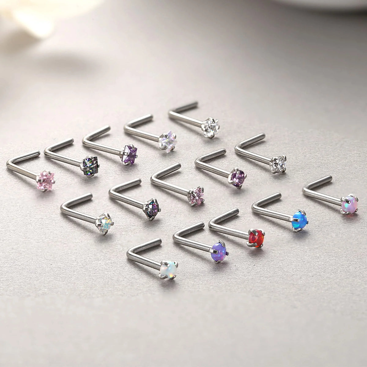 A collection of surgical stainless steel nose piercing studs in various gemstone colors and clear stones.